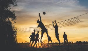 People playing beach volleyball during a sunset
